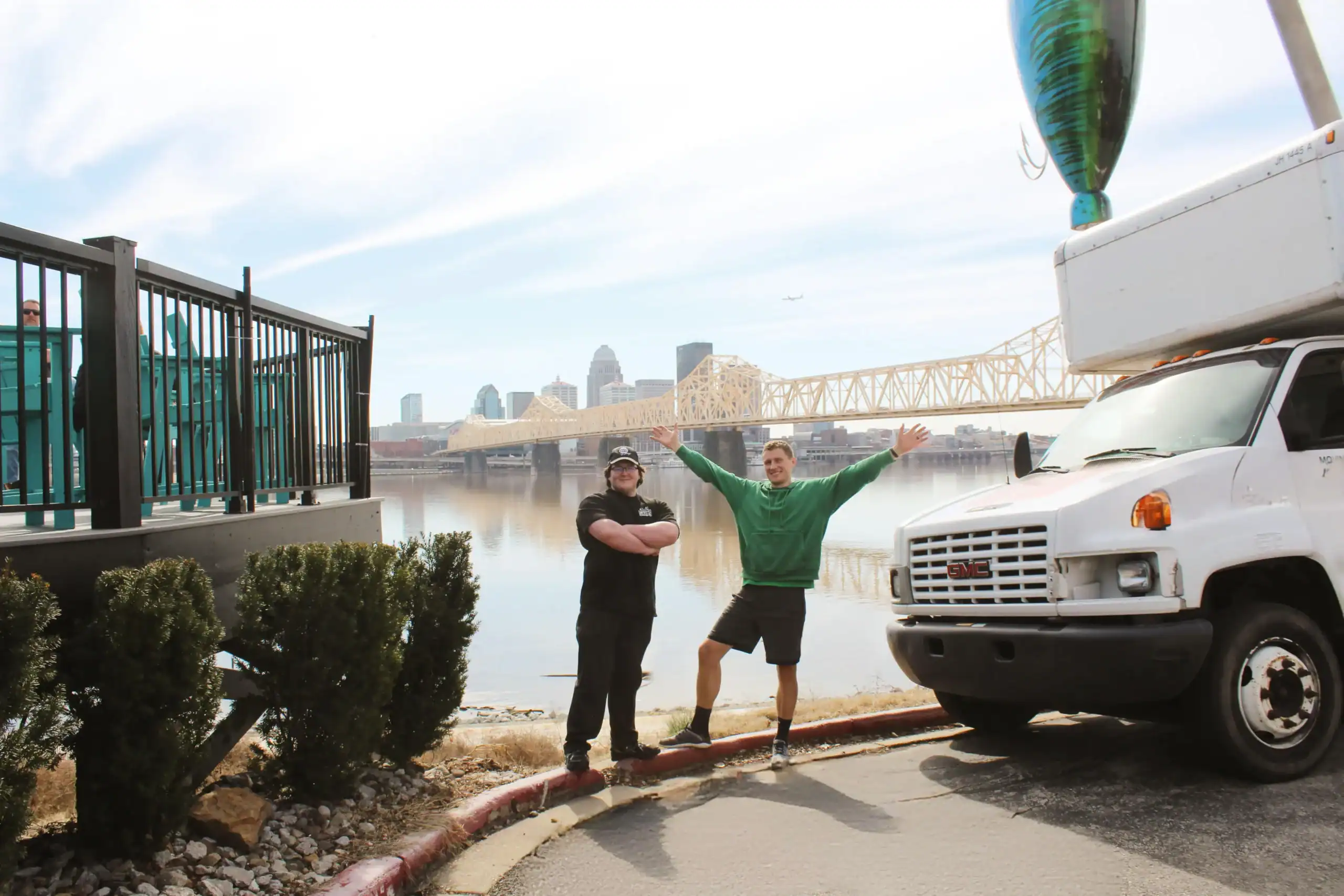 Horsepower Moving team beside a moving truck with the Clark Memorial Bridge and Louisville skyline in the background.